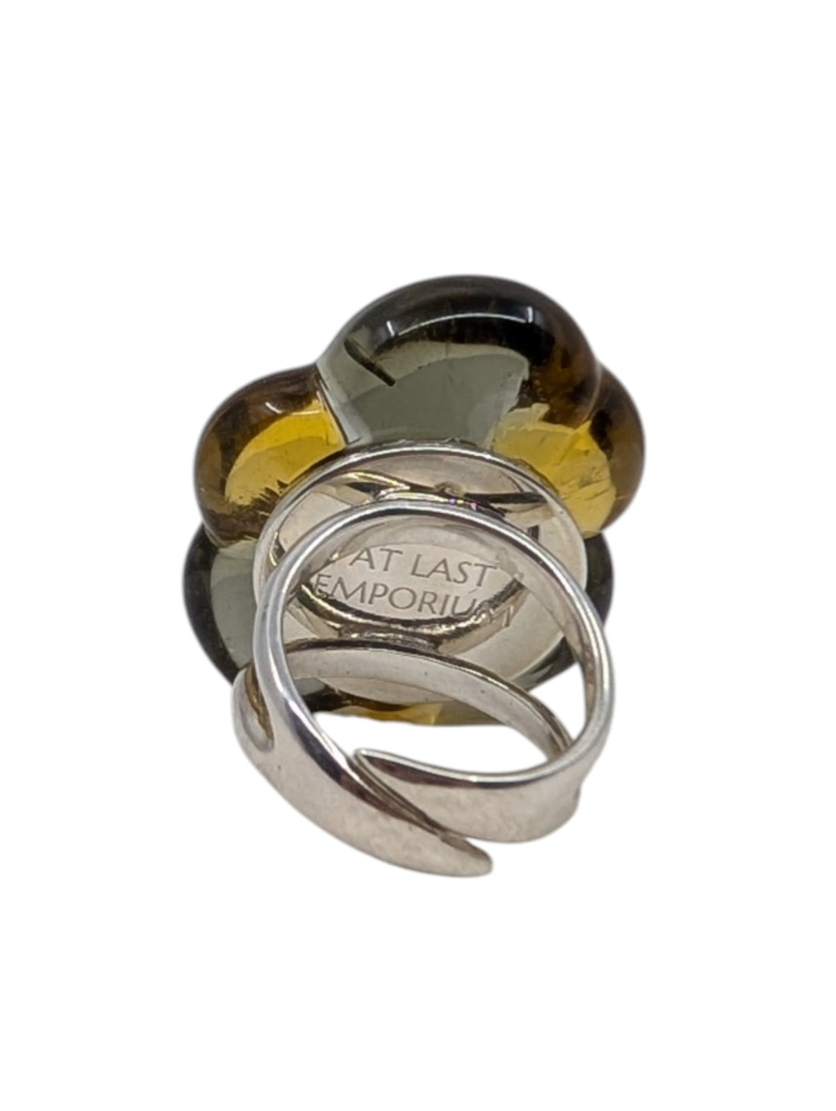 A silver-toned open band ring with a large flower-shaped cluster of translucent amber and smoky brown glass, photographed on a plain white background.