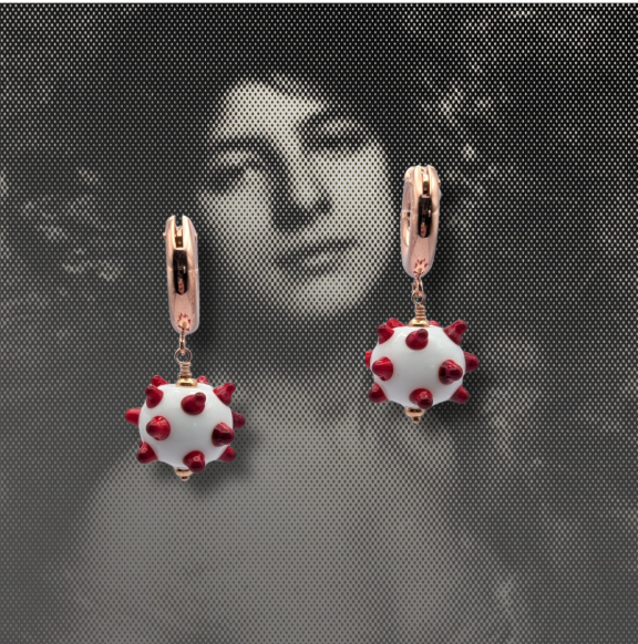 A pair of round black pendant earrings with silver fishhook ear wires, featuring millefiori pink flowers and green stems, displayed on a bed of sparkling peach-coloured beads. all murano glass.