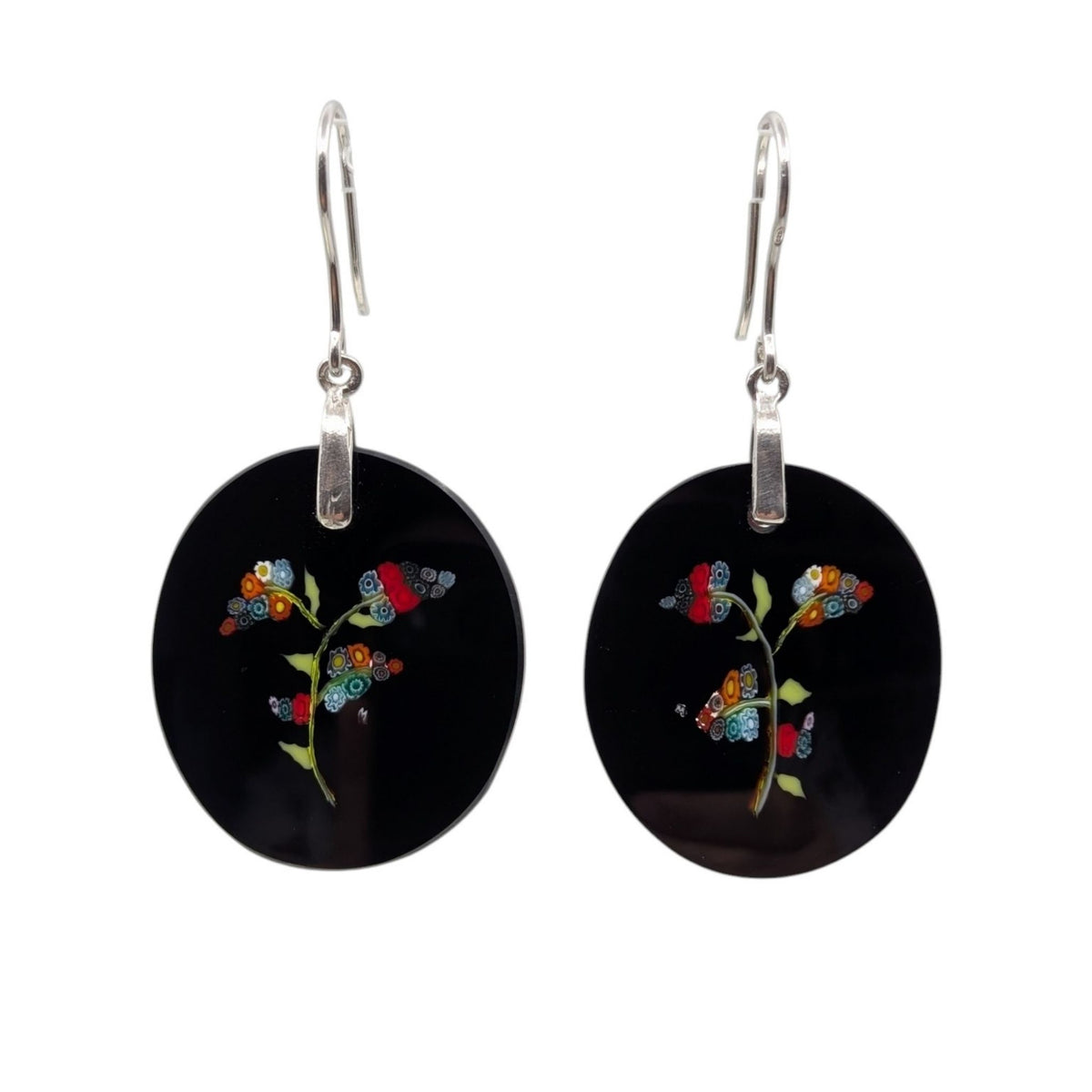 A pair of black oval dangle earrings with silver fishhook wires and colorful floral motifs, shown against a plain white background.