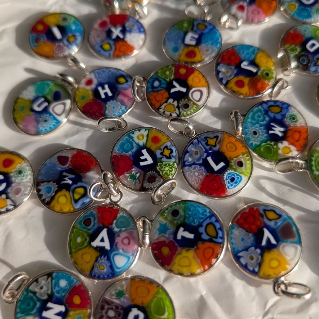 Multiple colourful Murano glass round pendant charms with silver lettering and silver jump rings, with alphabet letters.