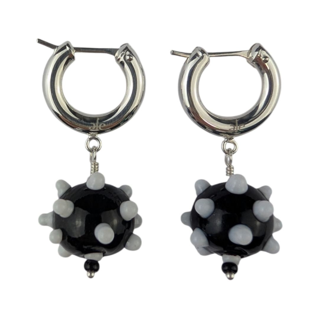 A pair of black and white earrings with glass beads and metallic rings.