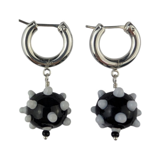 A pair of black and white earrings with glass beads and metallic rings.