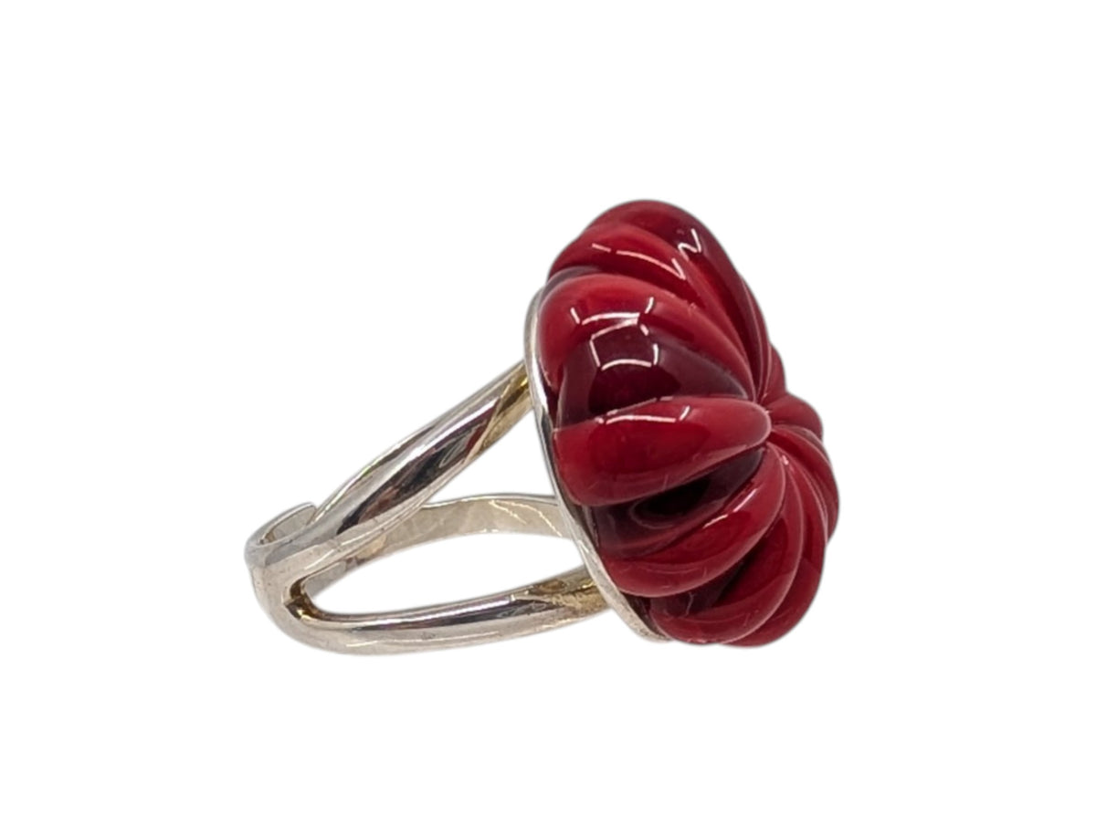 A silver ring featuring a large, sculpted red stone or resin flower-like centerpiece, shown against a plain white background.