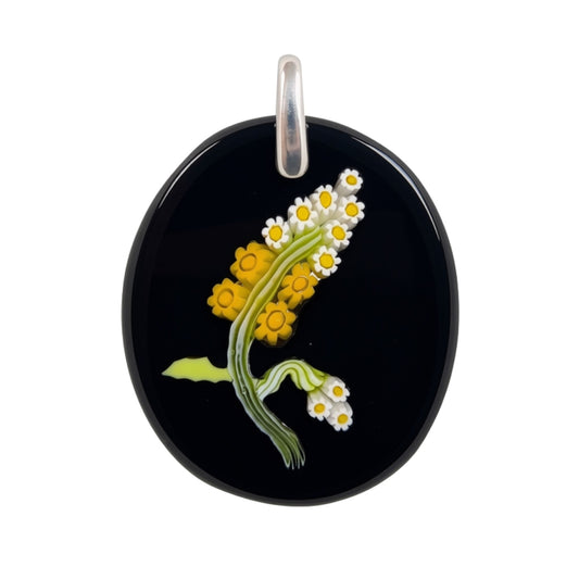 An oval black glass pendant featuring a  floral design of yellow and white daisies with green stems, complete with a silver-tone bail at the top, shown against a plain white background.